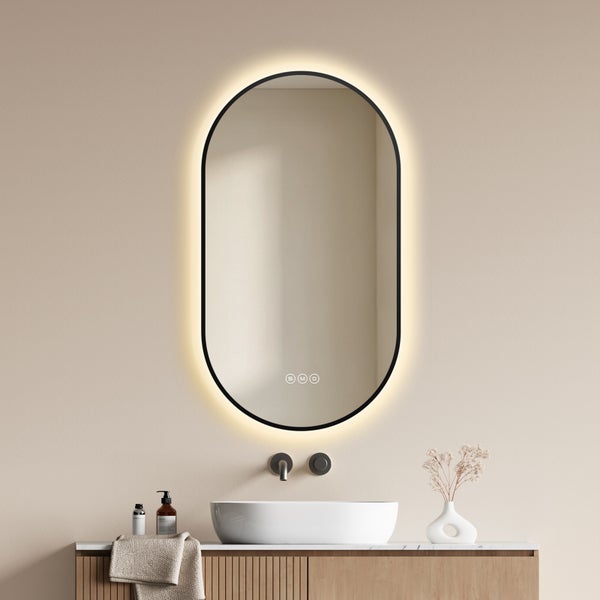 Ovaler LED Badezimmerspiegel mit schwarzem Rahmen und Touch Steuerung über einem Waschbecken auf einem Holzunterschrank.