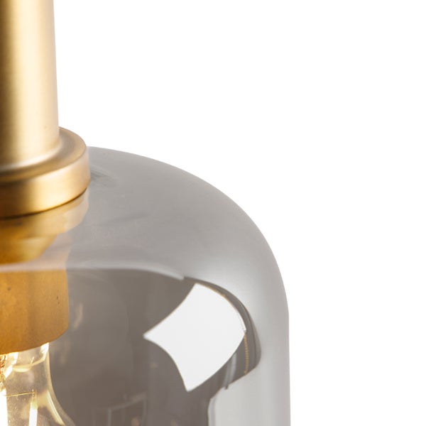 Nahaufnahme einer Pendelleuchte mit goldfarbener Metallfassung und einem Schirm aus rauchgrauem Glas.