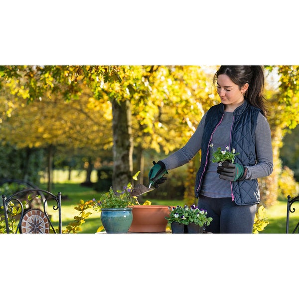 Frau pflanzt Blumen in Pflanzgefäße im Garten.