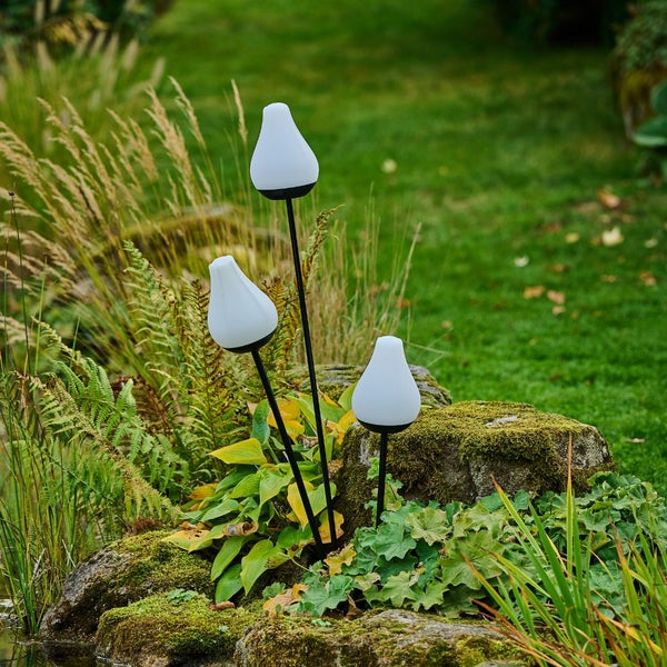 Szene mit drei Gartenleuchten mit Erdspieß im Gartenbereich.