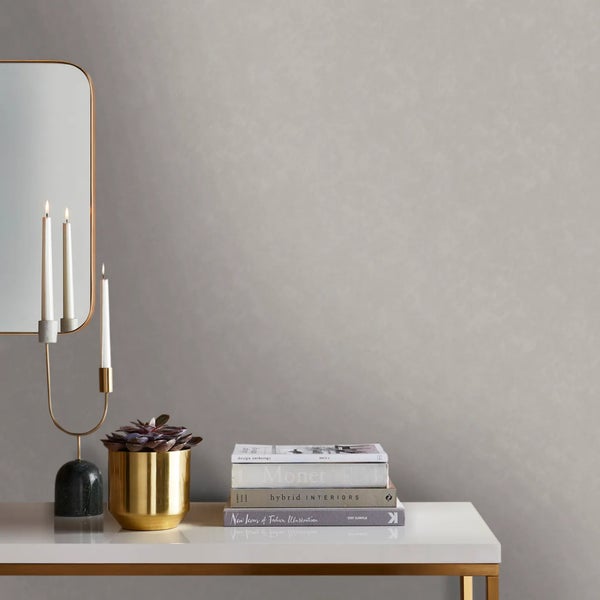 Wandgestaltung mit Tapete, Spiegel, Kerzenhalter, Pflanztopf und Büchern auf einem Tisch.