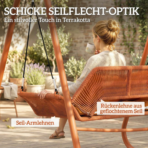 Person auf einer Gartenschaukel mit Rückenlehne und Armlehnen aus geflochtenem Seil in Terrakotta auf einer hellen Holzterrasse.