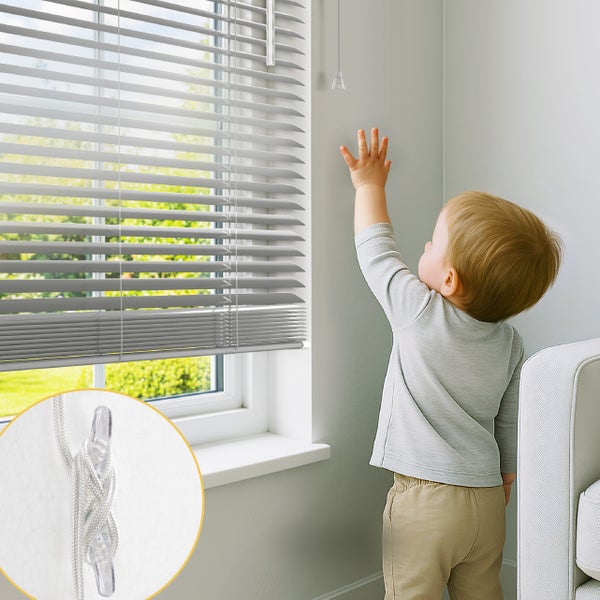 Kleinkind greift nach einer Jalousieschnur an einem Fenster, mit einer Detailansicht einer Kindersicherung für Zugschnüre an der Wand.