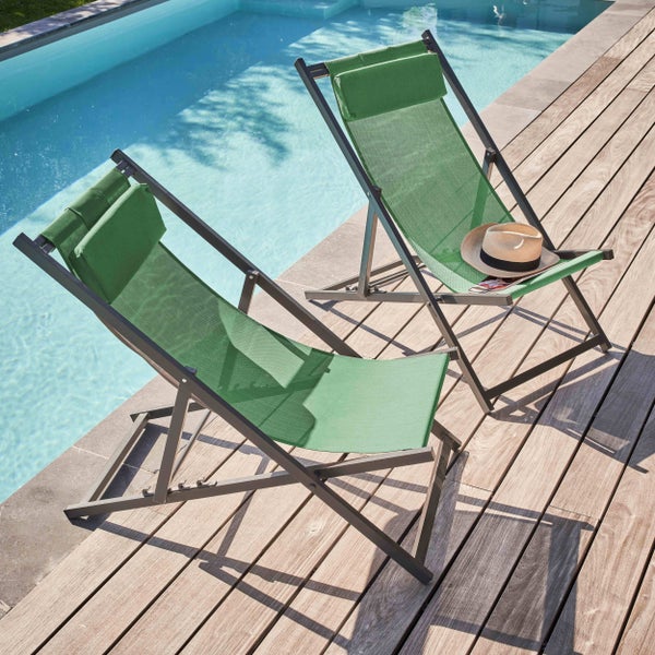 Zwei grüne Garten-Klappstühle mit Kopfkissen auf einer Holzterrasse neben einem hellen Swimmingpool.