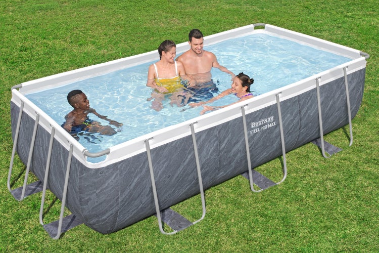 Eine Familie nutzt einen rechteckigen Bestway Steel Pro Max Aufstellpool mit Steinoptik auf einer Rasenfläche.