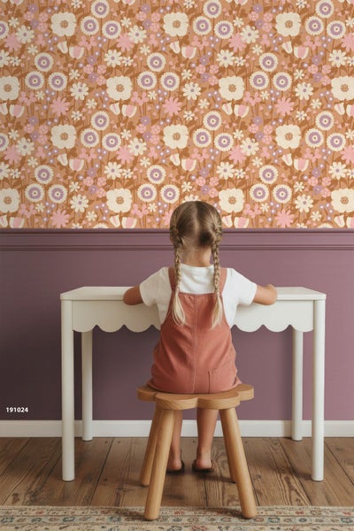 Wandgestaltung im Kinderzimmer mit floraler Vliestapete im Retro-Stil über einem Schreibtisch und einem Mädchen auf einem Holzschemel.