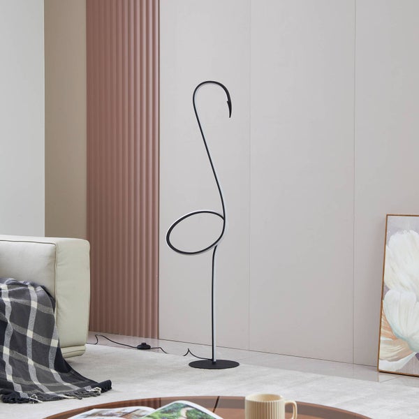 Moderne LED-Stehleuchte mit geschwungenem schwarzem Metallgestell und weißem LED-Band in einem hellen Wohnzimmer neben einem Sofa.