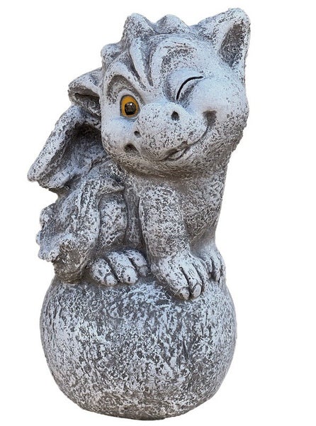 Gartenfigur kleiner Drache aus Steinguss, sitzend auf einer Kugel und zwinkernd, wetterfeste Dekofigur für den Außenbereich.