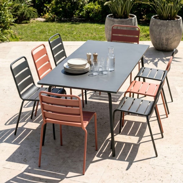Moderne Garten-Sitzgruppe auf einer Steinterrasse mit einem rechteckigen Metalltisch und acht stapelbaren Gartenstühlen im Latten-Design.