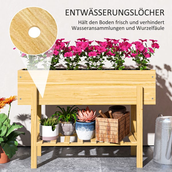 Hochbeet aus Holz mit Pflanzen und Gartengeräten im Garten