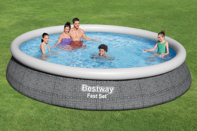 Eine fünfköpfige Familie spielt in einem runden Bestway Fast Set Aufstellpool mit Rattan-Muster. Die Szene wirkt hell und weitläufig.