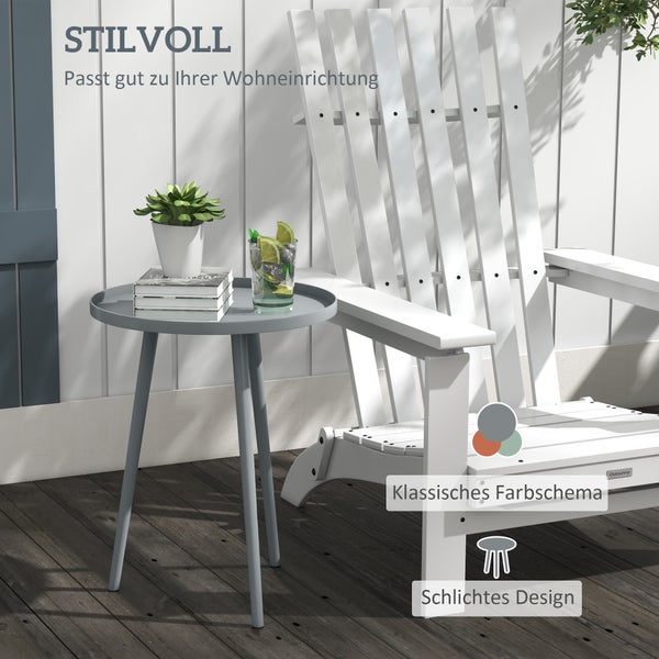 Weißer Adirondack Gartenstuhl und grauer runder Beistelltisch auf einer Holzterrasse vor einer weißen Holzwand mit Pflanze und Getränk.