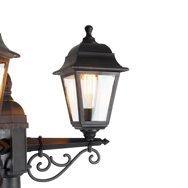 Klassische Außenleuchte in Laternenform aus Metall mit klarem Glas und dekorativem Arm, inklusive warmweißer LED-Glühlampe.