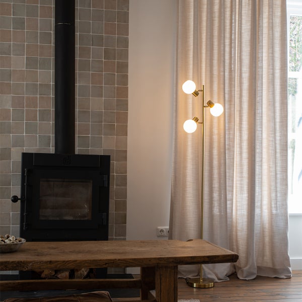 Wohnzimmer mit Kamin, Holztisch, Stehlampe und Vorhang