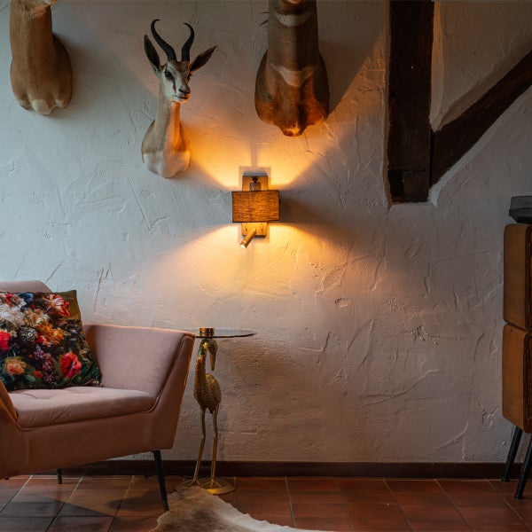 Wohnzimmer mit Sessel, Beistelltisch, Wandleuchte und Tierpräparaten