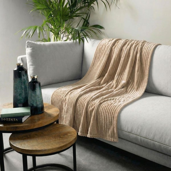 Wohnzimmer-Szene mit Sofa, Zierkissen, Tagesdecke, Beistelltischen, Dekovasen, Buch und Zimmerpflanze