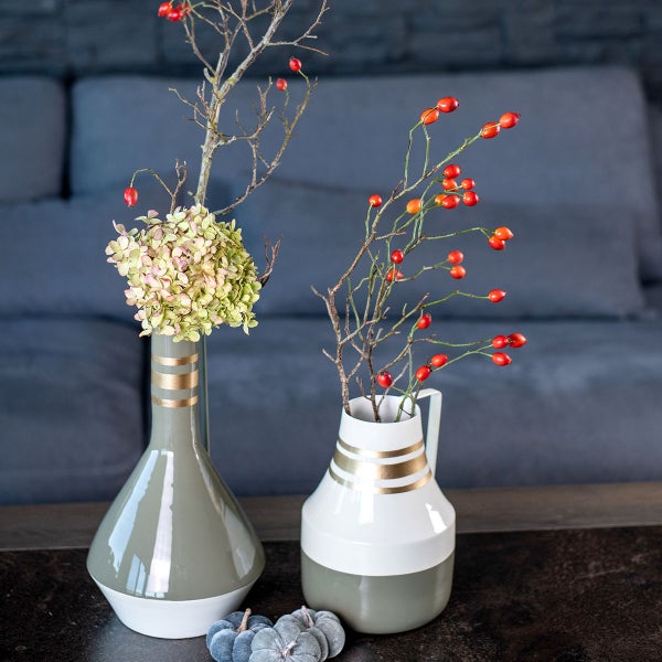 Dekorative Vasen mit Blumen und Zweigen auf einem Tisch