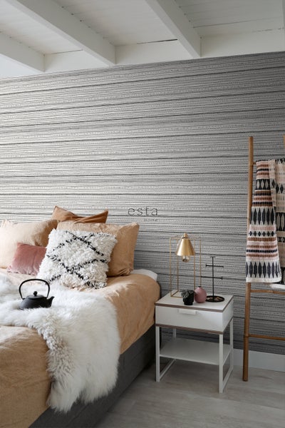 Schlafzimmer mit Bett, Nachttisch und gemusterter Tapete für eine gemütliche Atmosphäre