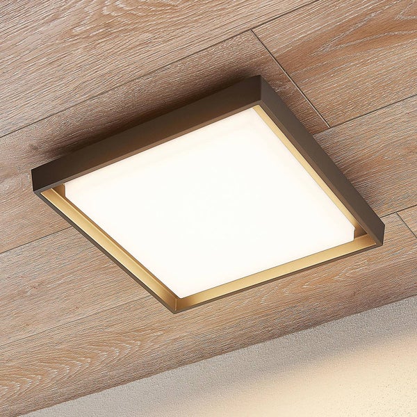 Quadratische LED-Deckenleuchte mit dunklem Metallrahmen und goldfarbener Innenkante an einer Holzdecke.