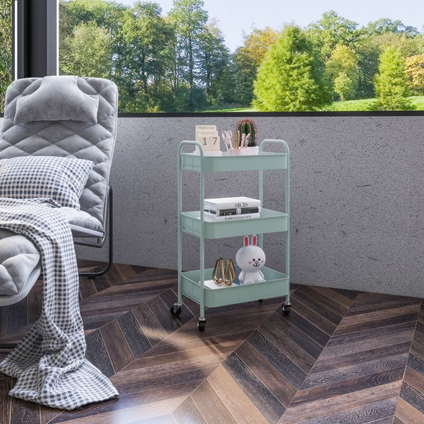 Moderner dreistufiger Rollwagen aus Metall in einem hellen Raum mit Fischgrätparkett, Polstersessel und großem Fenster zum Wald.