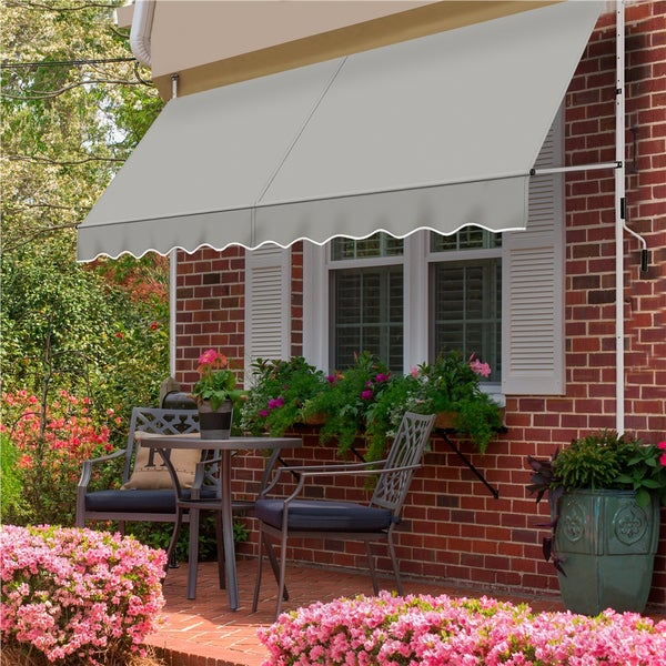 Szene mit Markise über einer Terrasse mit Tisch und Stühlen vor einem Haus mit Fensterkästen.