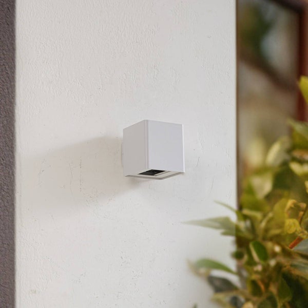 Weiße würfelförmige Außenwandleuchte an einer Wand montiert.