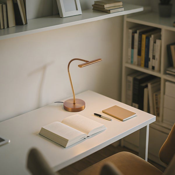 Schreibtisch mit Schreibtischlampe, Notizbuch und Stift in einem hellen Arbeitszimmer