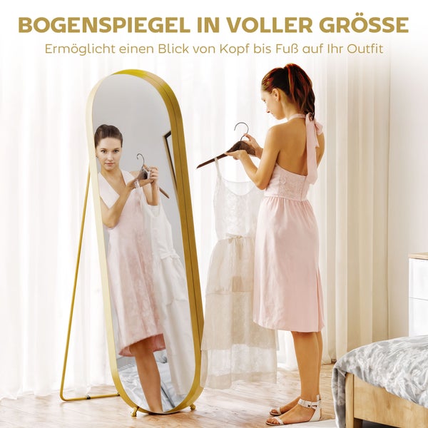 Freistehender Ganzkörperspiegel im Schlafzimmer mit einer Frau, die ihr Outfit betrachtet.