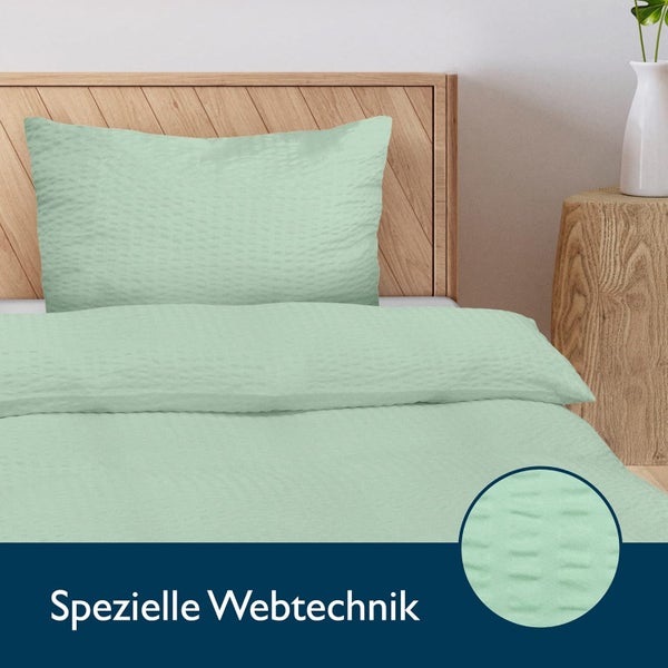 Bettwäsche-Set mit Kissenbezug und Deckenbezug aus Stoff mit spezieller Webtechnik auf einem Holzbett.