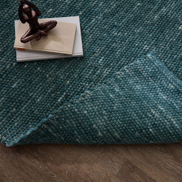 Nahaufnahme eines gewebten Teppichs mit Büchern und einer Statue