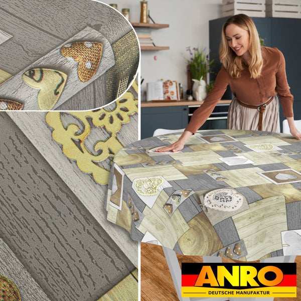 Eine Frau streicht eine runde Tischdecke mit Patchwork-Muster in Holzoptik und Herzmotiven auf einem Tisch glatt. Detailansicht der Textur. ANRO Logo.