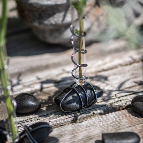 Dekorative Glasvase mit Stein und Draht auf Holz