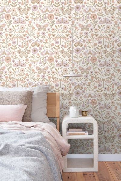Schlafzimmer mit Bett und Nachttisch vor einer floralen Tapete mit Schmetterlingsmuster.
