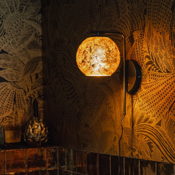 Wandleuchte mit Kugelglas-Schirm und dunkler Halterung in einem Badezimmer mit gemusterter Tapete
