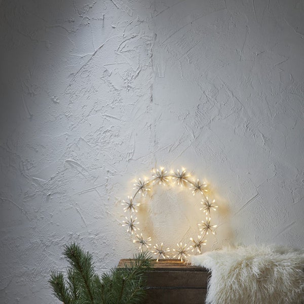 Leuchtender Sternenkranz als Dekoration auf einer Holzbox mit Fell