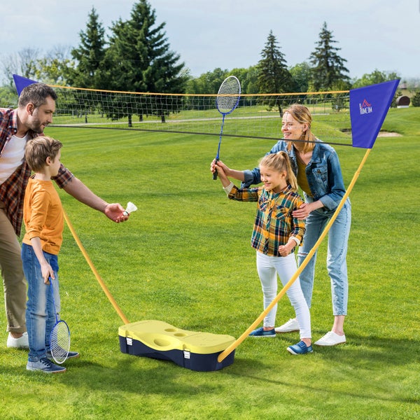 Mobiles Badminton-Set mit Netz und Schlägern, genutzt von einer Familie auf einer Wiese im Freien.