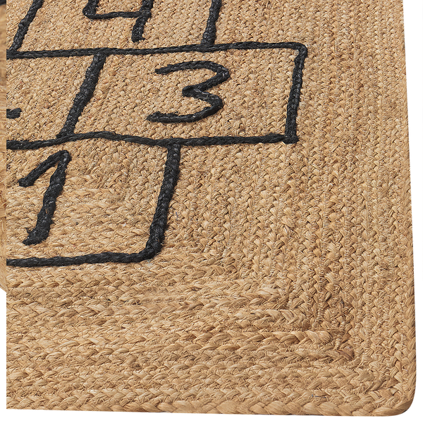 Nahaufnahme eines Jute-Teppichs mit einem Hüpfspiel-Muster aus Zahlen und Feldern.