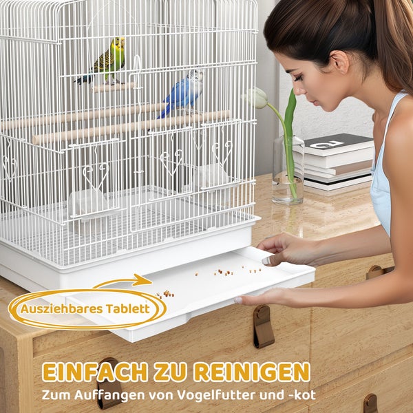 Vogelkäfig mit ausziehbarem Tablett zur einfachen Reinigung von Futterresten und Kot, auf einer Kommode stehend, mit zwei Wellensittichen im Inneren.
