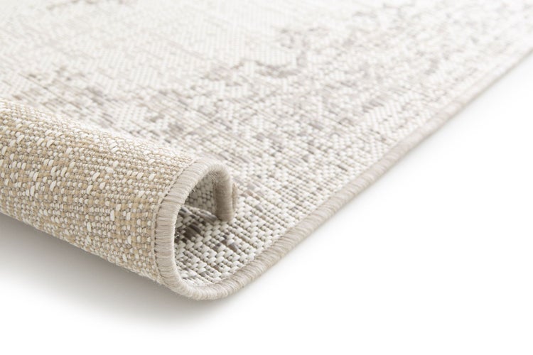 Flachgewebter Teppich in Beige mit dezentem Muster, strukturierter Oberfläche und umgeschlagener Kante.