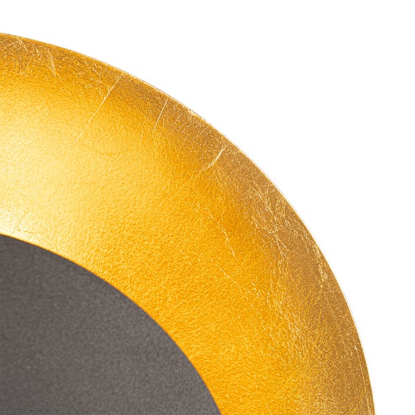 Detailaufnahme einer runden, goldenen Wandleuchte