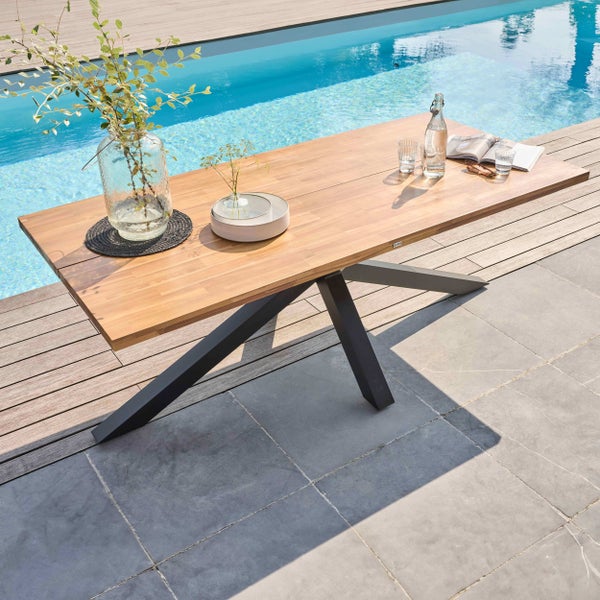 Moderner rechteckiger Gartentisch mit Holzplatte und dunklem Metallgestell auf einer hellen Terrasse an einem Pool.