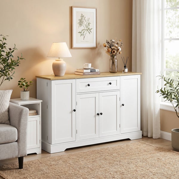 Weißes Sideboard im Landhausstil mit Holzplatte, vier Türen und einer Schublade in einem hellen, organisierten Wohnzimmer mit Juteteppich.