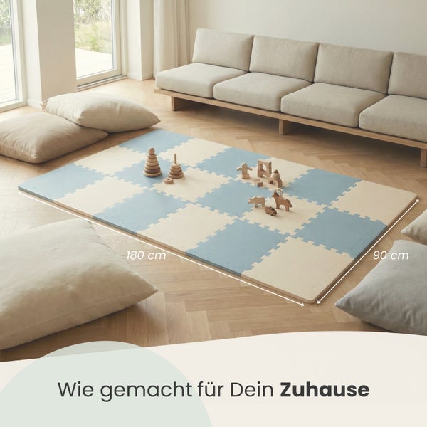 Schaumstoff-Puzzlematte für Kinder, 180 mal 90 Zentimeter, in einem hellen Wohnzimmer mit Holzfussboden und Sofa.