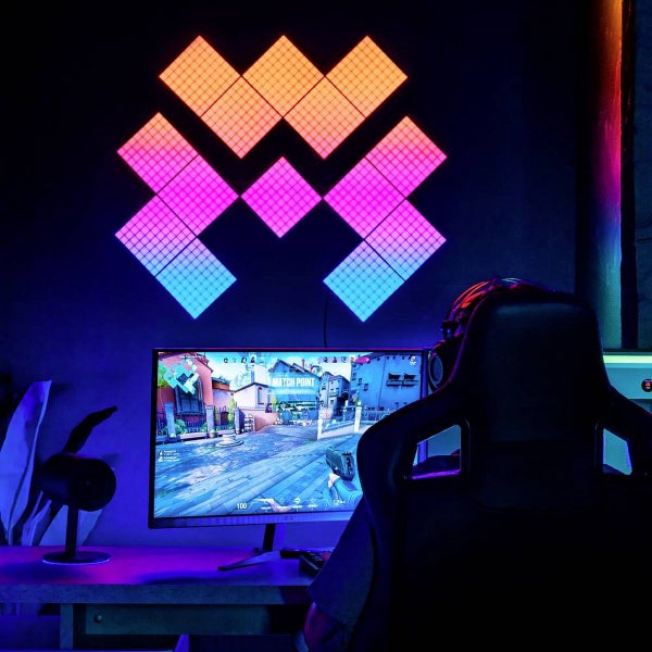 Dekorative Wandleuchtenpaneele in einem Gaming-Setup mit einem Gamer vor einem Computerbildschirm.