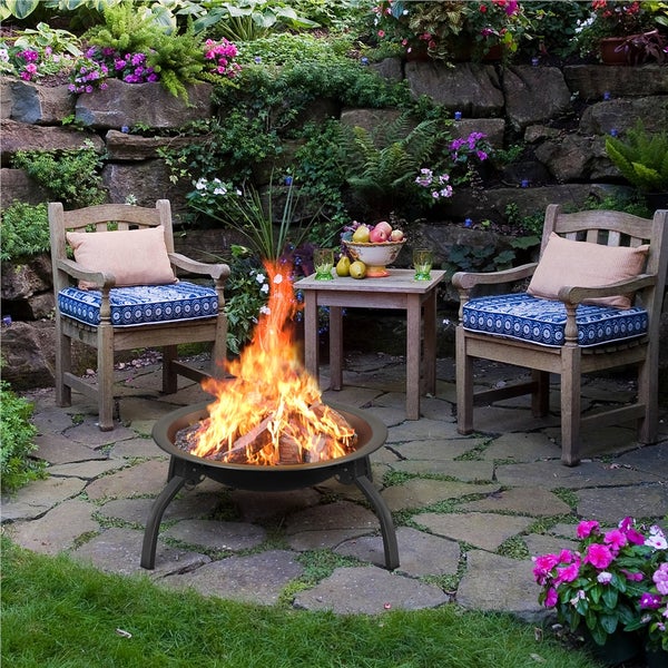 Feuerstelle mit Holz auf einer Terrasse mit zwei Stühlen und einem Tisch