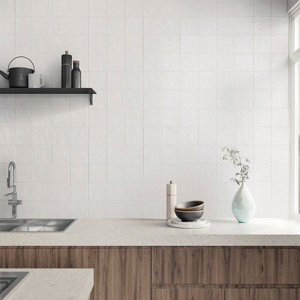 Moderne Küche mit quadratischen Wandfliesen, dunklen Holzfronten, hellen Arbeitsplatten und einer schwarzen Wandablage.