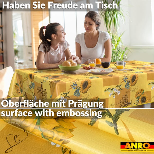 Abwischbare Tischdecke mit Sonnenblumenmuster auf gedecktem Tisch in hellem Raum mit zwei Personen. Detail zeigt geprägte Oberfläche. ANRO Logo.