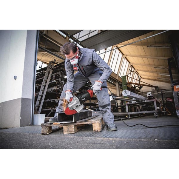 Handwerker mit Schutzausrüstung schneidet Metallrohr mit einem Flex Winkelschleifer in einer Werkstatt