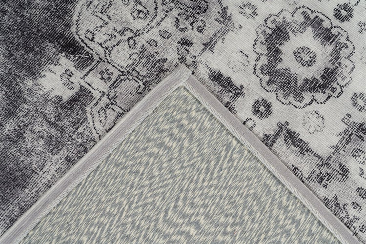 Nahaufnahme eines Vintage-Teppichs mit orientalischem Muster, sichtbarem Teppichrücken und gekettelter Kante.