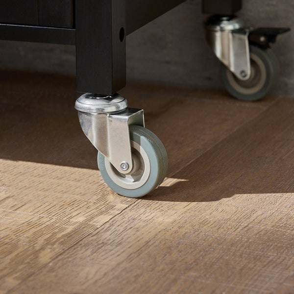 Detailaufnahme eines Möbelstücks mit Rollen auf einem Holzboden